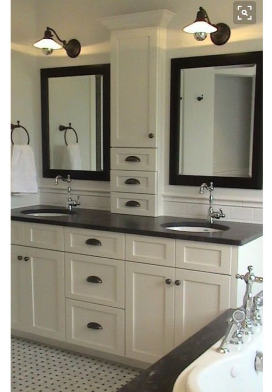 White double vanity with a dark countertop, two framed mirrors and a tall centre cabinet