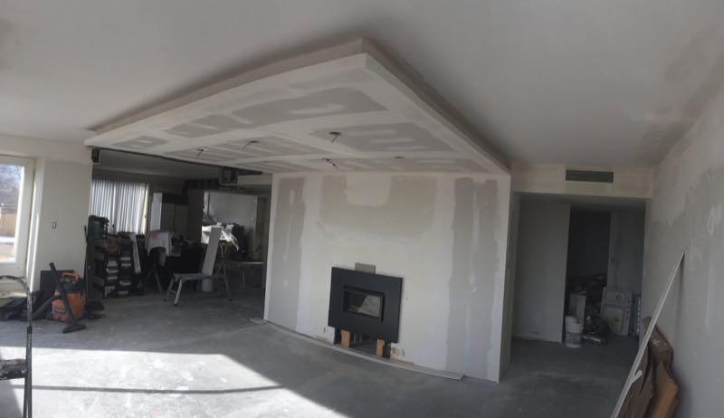 Open room at the drywall stage, with a feature ceiling and a fireplace wall