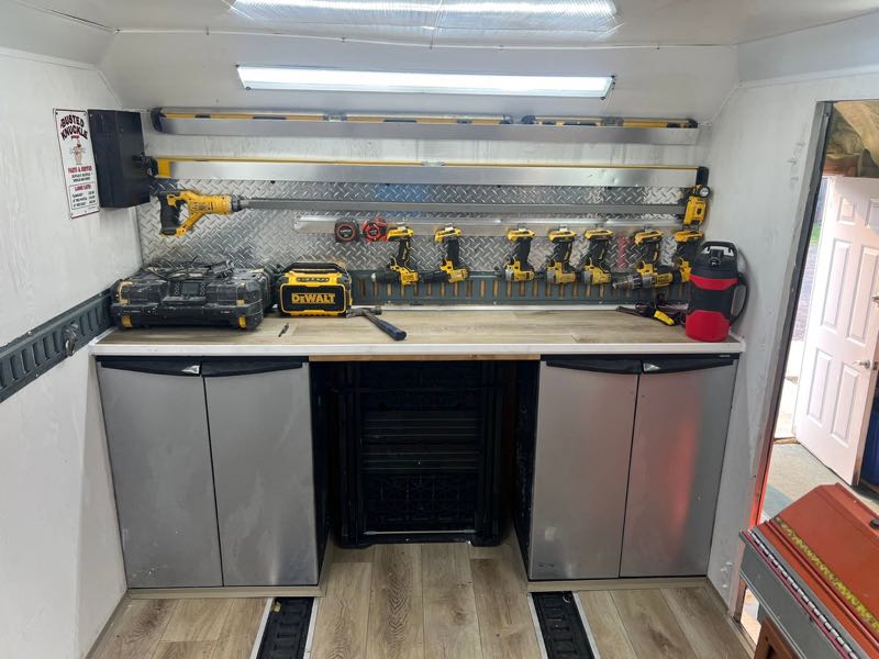 Inside the trailer: a workbench and a wall of cordless tools on racks